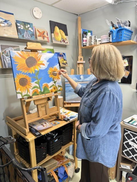 Juli Luckett painting sunflowers at her easel