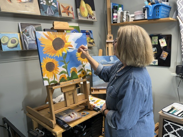 Close view of Juli painting a sunflower canvas